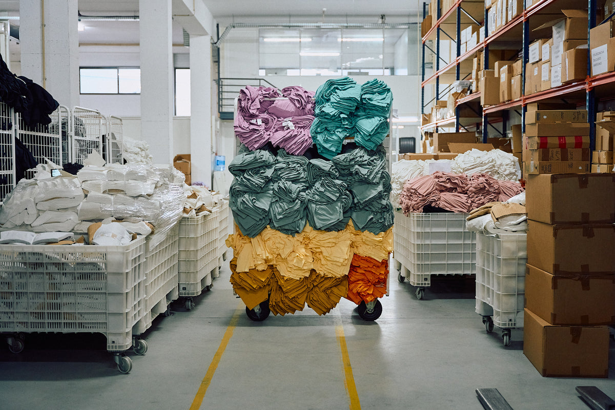 Colorful Fabrics on wheels in a warehouse setting with shelves and crates.